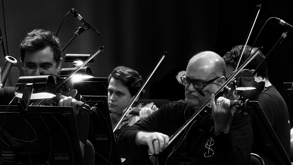 Músicos de orquestra tocando violino, em preto e branco